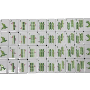 May include: A set of white Mahjong tiles with green bamboo and dragon illustrations. Each tile displays a number from 1 to 9. The tiles are arranged in rows and columns, showcasing the variety of designs.