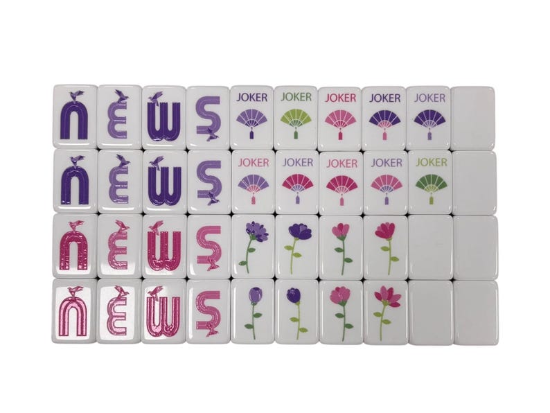 May include: A set of white Mahjong tiles. Some tiles feature the word "NEWS" in purple and pink, while others display fan and flower designs. The word "JOKER" is printed on some tiles.