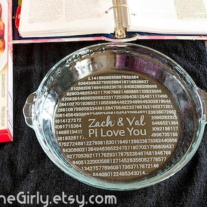 May include: A clear glass pie dish with handles, featuring engraved text and numbers. The text reads "Zach & Val Pi Love You" with the digits of pi surrounding the text. A box of pie crusts is visible.