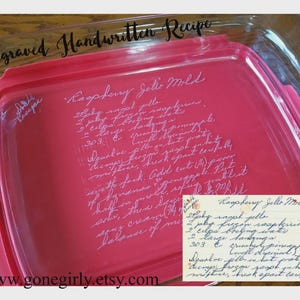 May include: A red rectangular container with a handwritten recipe for "Raspberry Jello Mold" engraved on the lid. The text "Engraved Handwritten Recipe" is above the container. A smaller recipe card is in the bottom right corner.