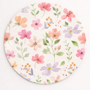 May include: Round coaster with a watercolor floral design. The coaster features a cream background with scattered flowers in shades of pink, peach, and lavender, along with green leaves and orange berries.