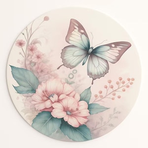 May include: A round decorative piece featuring a watercolor design of a butterfly and flowers. The butterfly has light blue and mauve wings. Pink flowers and green leaves surround the butterfly. The background is a soft pink.