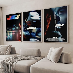 May include: Three framed movie posters with the text "HURRY UP TOMORROW" in a colorful font. The posters feature blurred images of faces and cityscapes. The date "MAY 16" is visible on two posters.