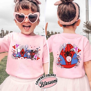 Pu&ograve; includere: Una maglietta rosa con un design di Spider-Man. La parte anteriore della maglietta mostra il nome "JACK" con grafica di Spider-Man e dettagli di ragnatela. Il retro presenta un grande emblema di Spider-Man. La maglietta ha il testo "COMFORT COLORS Blossom".