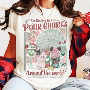 May include: Cream-colored t-shirt with a colorful graphic design. The design features the text "I'm Making Pour Choices Around the World" with illustrations of festive drinks. The shirt includes a list of countries.