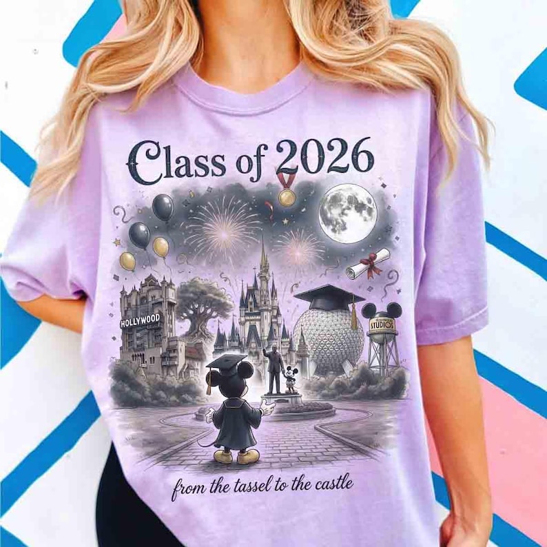 May include: A light purple t-shirt with the text "Class of 2026" and a graphic of a graduation scene at a theme park. The graphic includes fireworks, a full moon, and Mickey Mouse. The text "from the tassel to the castle" is at the bottom.