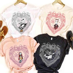 May include: Four t-shirts with different colors and designs. Each shirt features a heart-shaped graphic with characters from "The Nightmare Before Christmas" and the text "The Nightmare Before Christmas".