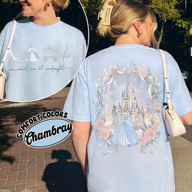May include: Light blue Comfort Colors Chambray t-shirt featuring a Cinderella theme. The front has a shoe, dress, carriage, and castle with "meet me at midnight" text. The back has a castle, Cinderella, and floral design.