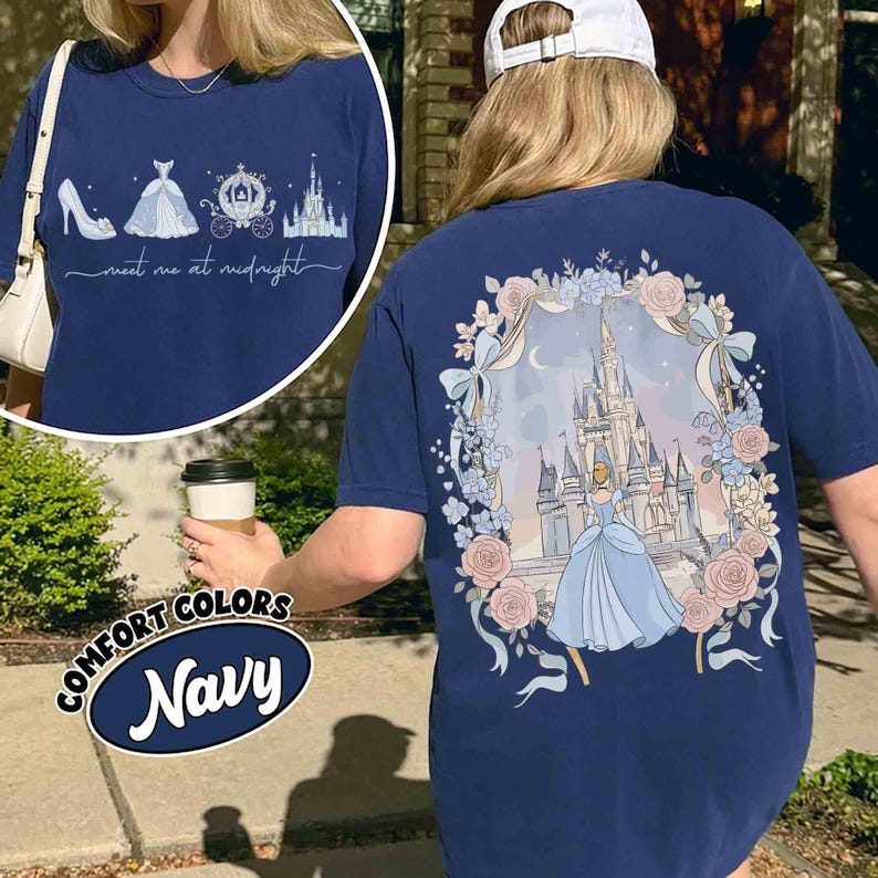 May include: Navy blue Comfort Colors t-shirt featuring a Cinderella theme. The front has a shoe, dress, carriage, and castle graphic with the text "meet me at midnight." The back displays Cinderella in front of a castle, surrounded by flowers and bows.