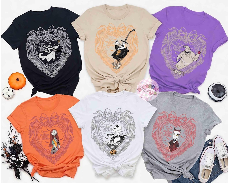 May include: A collection of six t-shirts in various colors, each featuring a heart-shaped design with characters from "The Nightmare Before Christmas." The designs include Jack Skellington, Sally, and Oogie Boogie. The shirts are displayed with Halloween-themed decorations.