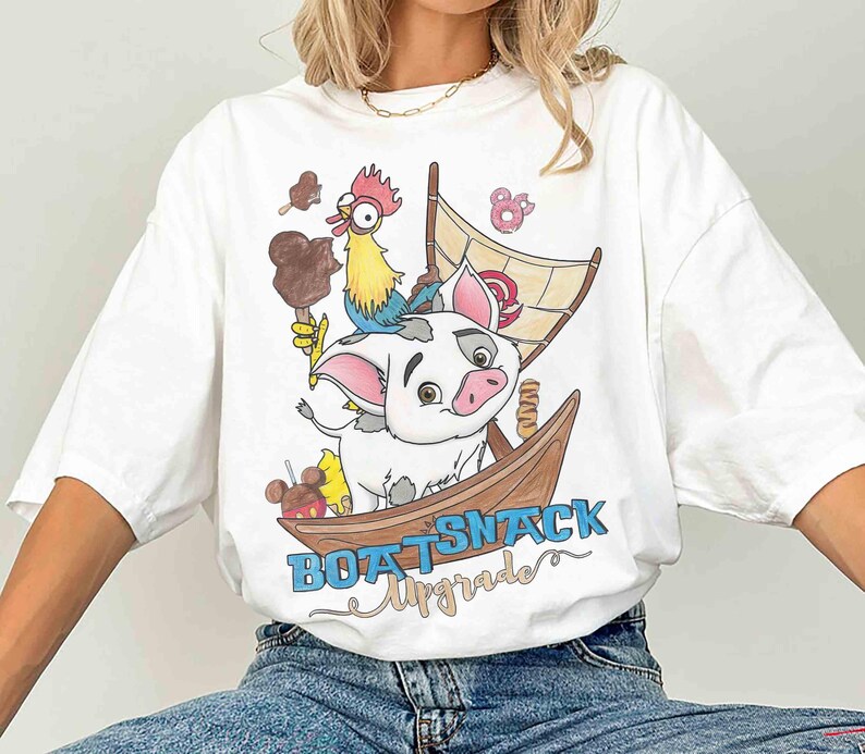 May include: White t-shirt featuring a cartoon illustration of a pig, rooster, and boat with the text "BOAT SNACK Upgrade". The design includes ice cream and a sail. The shirt is a casual, oversized fit.