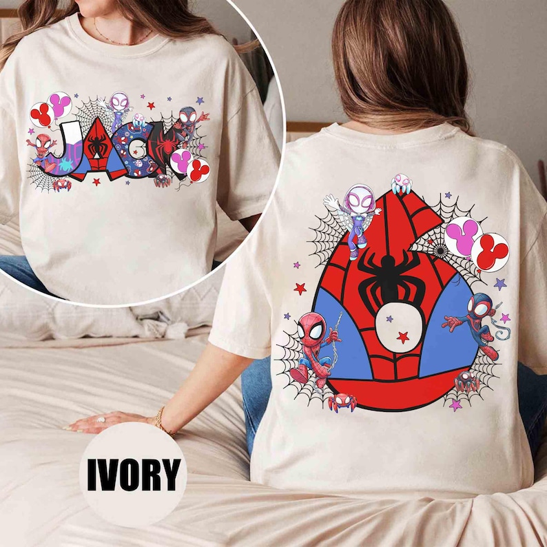 Pu&ograve; includere: T-shirt color avorio con la scritta "JASON" in un font colorato in stile fumetto, ragnatele e grafica di personaggi. Il retro mostra un grande emblema di Spider-Man con illustrazioni di personaggi e stelle.
