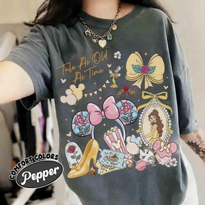 Puede incluir: Camiseta Comfort Colors gris oscuro con un gráfico colorido que presenta elementos de La Bella y la Bestia, incluyendo a Bella, un tacón alto y el texto "Tale As Old As Time". La camiseta también tiene un diseño de diadema de orejas de Mickey Mouse.