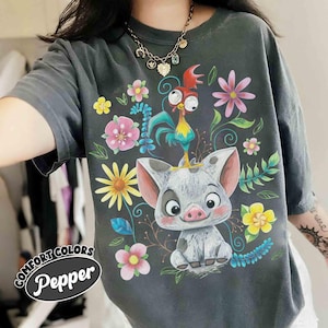 May include: Dark grey t-shirt with a vibrant graphic of a pig and rooster amidst flowers. The shirt displays the words "COMFORT COLORS" and "Pepper". It's a loose-fitting style, perfect for casual wear.