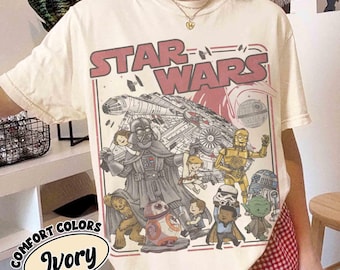 Könnte beinhalten: Elfenbeinfarbenes T-Shirt mit einem Star Wars-Motiv. Das Design zeigt den Text "STAR WARS" in Rot sowie Illustrationen von Darth Vader, dem Millennium Falken und anderen Charakteren. Das T-Shirt ist mit "COMFORT COLORS Ivory" gekennzeichnet.