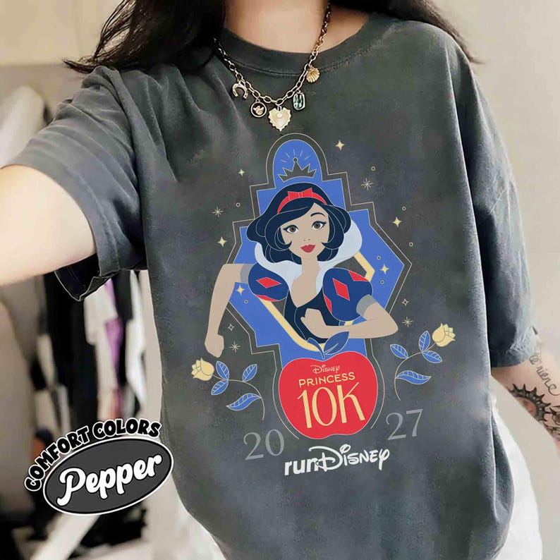 May include: Dark gray Comfort Colors t-shirt with a graphic of Snow White from Disney's Snow White and the Seven Dwarfs. The graphic includes the text "Disney Princess 10K" and "runDisney". The shirt also has the text "20 27".