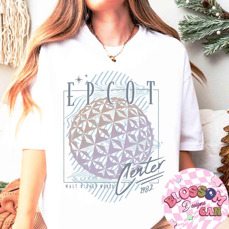May include: White t-shirt featuring a graphic design with the text "EPCOT Center" and a geometric sphere design. The design includes the text "WALT DISNEY WORLD" and "1982". The shirt is a crew neck.
