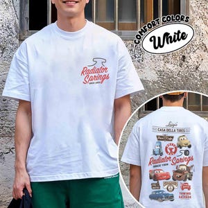 May include: A white short-sleeve t-shirt featuring a small red Radiator Springs Since 1909 logo on the front chest. The back displays a large graphic with various characters and locations from the movie Cars, including text like Luigi's Casa Della Tires.