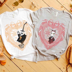 May include: Two t-shirts with heart-shaped designs from "The Nightmare Before Christmas." One is white with an orange design of Jack Skellington. The other is gray with a pink design of a character. Both shirts have the text "The Nightmare Before Christmas."