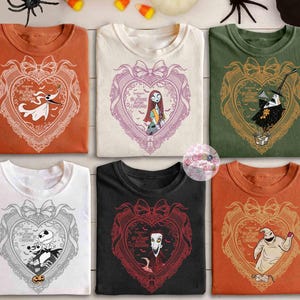 May include: Six t-shirts in various colors, each featuring a heart-shaped design with characters from "The Nightmare Before Christmas." The designs include Zero, Sally, Jack Skellington, and Oogie Boogie. The shirts are orange, white, green, black, and white.