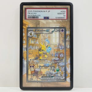 Puede incluir: Una tarjeta coleccionable Pokemon M-P JP Pikachu McDonald's 2025 graduada por PSA en un estuche de plástico negro. La tarjeta muestra a Alakazam ex con 310 HP, ataques Mind Jack y Dimensional Hand, sobre una ilustración de un taller de madera.