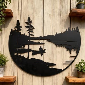 Puede incluir: Arte de pared de metal negro que representa una escena de lago serena con una persona en canoa, árboles y montañas. La obra de arte está montada en una pared de madera, rodeada de pequeñas plantas en macetas y estantes de madera.