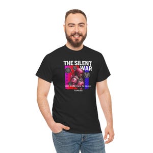 Può includere: T-shirt nero con la scritta "THE SILENT WAR" e un'illustrazione di un personaggio futuristico con un'armatura rosa e rossa. La grafica include il testo "SOULS RESONATE WITH THE PULSE OF TECHNOLOGY".