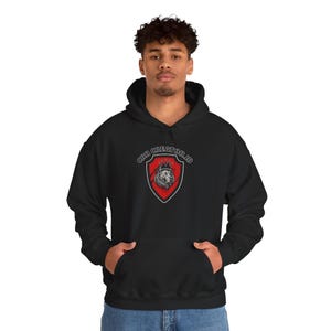 May include: Black hooded sweatshirt with a kangaroo pocket. The front displays a red shield design with a lion and the text "CBR CREATOR.ID" in white. The sweatshirt is made of a soft material and has a drawstring hood.