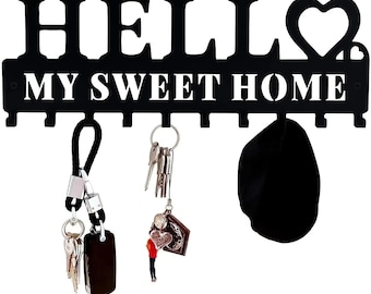 May include: Black metal key holder with the words "HELLO MY SWEET HOME" cut out. The key holder has a heart-shaped design and several hooks. Keys and a black pouch hang from the hooks.