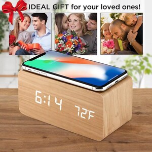 Puede incluir: Un despertador digital de madera con un smartphone encima. El reloj muestra la hora 6:14 y la temperatura 22°C. La imagen incluye el texto "IDEAL GIFT for your loved ones!"