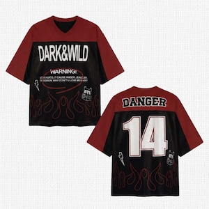 Puede incluir: Una camiseta negra y burdeos de estilo jersey con cuello en V. La parte delantera presenta el texto "DARK & WILD" y "WARNING!" con gráficos de llamas y texto. La parte trasera muestra "DANGER" y el número "14".