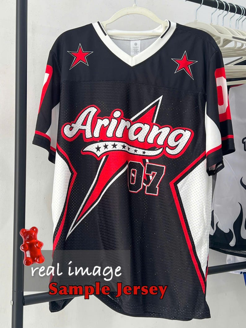 May include: Black jersey with red and white accents, featuring the word "Arirang" in white script with red accents. The jersey has red stars and the number "07". The text "real image Sample Jersey" is at the bottom.