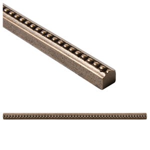 Puede incluir: Una moldura decorativa de metal con forma rectangular y una serie de pequeñas cuentas redondas y espaciadas uniformemente a lo largo de un borde. La moldura tiene un acabado metálico similar al bronce y se muestra en dos vistas sobre un fondo blanco.