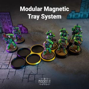 Può includere: Un sistema di vassoio magnetico modulare con alloggiamenti circolari neri e bordi gialli. Il vassoio contiene diverse miniature di soldati verdi in armatura. Il testo "Modular Magnetic Tray System" e "MISCAST.IT" è visibile nell'immagine.
