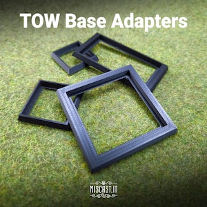 Könnte beinhalten: Auf einem grünen Untergrund sind mehrere schwarze, quadratische TOW-Basisadapter zu sehen. Der Text "TOW Base Adapters" befindet sich oben im Bild. Die Website "MISCAST.IT" ist unten.