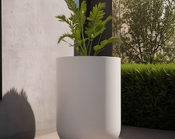 May include: A tall, cylindrical white planter with a smooth, matte finish. The planter features a rounded base and contains a vibrant green leafy plant with multiple fronds extending upwards from the center of the container.