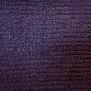 Può includere: Primo piano di un tessuto testurizzato di colore viola scuro con una superficie morbida e pelosa.