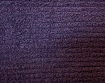 Puede incluir: Primer plano de una tela texturizada de color morado oscuro con una superficie suave y peluda.