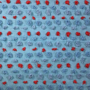 Può includere: Un tessuto testurizzato blu e rosso con un motivo ripetitivo di piccoli cerchi in rilievo. I cerchi sono di colore blu chiaro e sono circondati da un cerchio rosso.