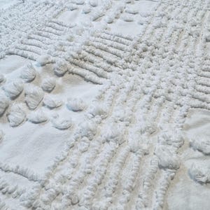Könnte beinhalten: Weiße, strukturierte Baumwoll-Decke mit einem erhabenen geometrischen Muster.