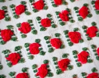 May include: White crocheted blanket with a repeating pattern of red roses. The roses are made with yarn and are raised from the surface of the blanket.