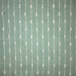 May include: A close-up of a light green fabric with a white dotted pattern. The fabric has a subtle texture and a slightly raised pattern.