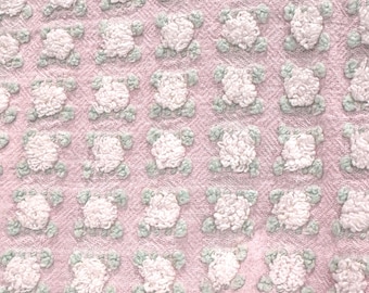 Puede incluir: Una tela rosa con un patrón repetitivo de formas blancas en relieve que parecen flores.