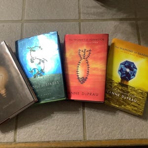 Puede incluir: Se muestran cuatro libros de tapa dura con cubiertas coloridas. Los t&iacute;tulos incluyen "The City Of", "People of Sparks", "The Prophet of Yonwood" y "The Diamond of Darkhold". Los libros son de Jeanne DuPrau.