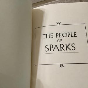 Puede incluir: P&aacute;gina de t&iacute;tulo de un libro abierto con el t&iacute;tulo "THE PEOPLE OF SPARKS" en negro. El t&iacute;tulo est&aacute; centrado dentro de un marco rectangular negro, con adornos decorativos arriba y abajo.