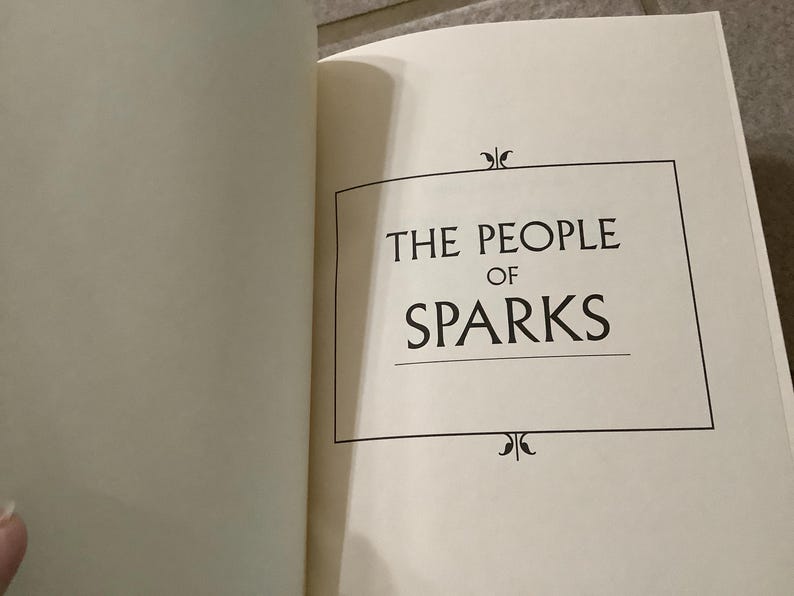 Puede incluir: P&aacute;gina de t&iacute;tulo de un libro abierto con el t&iacute;tulo "THE PEOPLE OF SPARKS" en negro. El t&iacute;tulo est&aacute; centrado dentro de un marco rectangular negro, con adornos decorativos arriba y abajo.