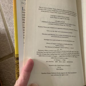 Puede incluir: Libro abierto con texto, incluyendo informaci&oacute;n de derechos de autor y n&uacute;meros ISBN. El texto menciona "The diamond of Darkhold" de Jeanne DuPrau, publicado por Random House Children's Books. El libro es una primera edici&oacute;n.