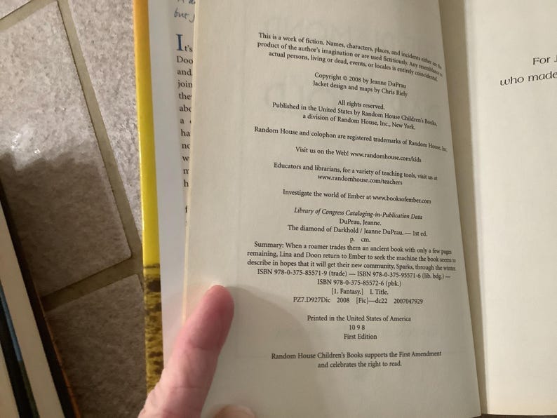 Puede incluir: Libro abierto con texto, incluyendo informaci&oacute;n de derechos de autor y n&uacute;meros ISBN. El texto menciona "The diamond of Darkhold" de Jeanne DuPrau, publicado por Random House Children's Books. El libro es una primera edici&oacute;n.