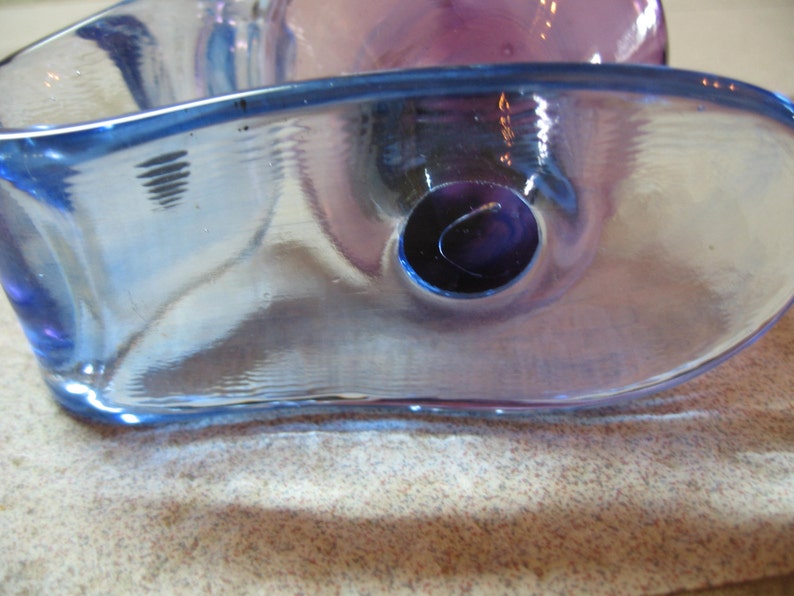 May include: A blue and purple glass bowl with a unique, wavy design. The bowl has a hole in the center.