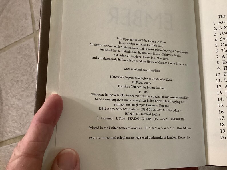 Puede incluir: P&aacute;gina abierta de un libro con texto de copyright de 2003 de Jeanne DuPrau. El texto describe el libro "The City of Ember" e incluye el ISBN y los datos de la Biblioteca del Congreso. Es una primera edici&oacute;n impresa en Estados Unidos.